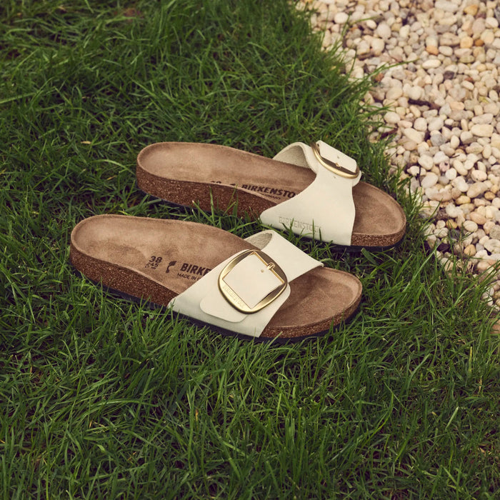 Pair of sandals with buckles on a grassy and pebbled surface