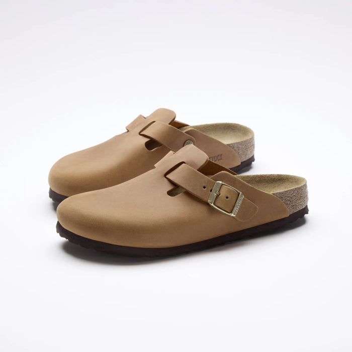 A pair of tan clog-style mules with adjustable double straps and metal buckles, displayed on a clean white background.