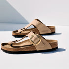 Pair of beige sandals with a buckle on a white background