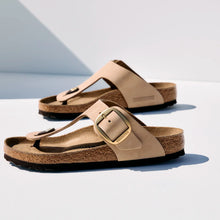 Pair of beige sandals with a buckle on a white background