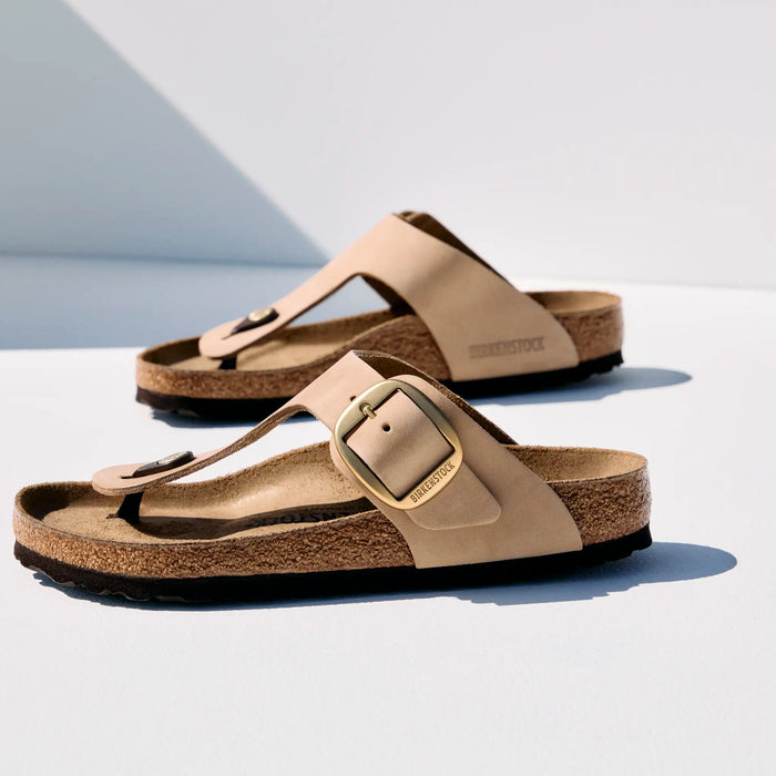 Pair of beige sandals with a buckle on a white background