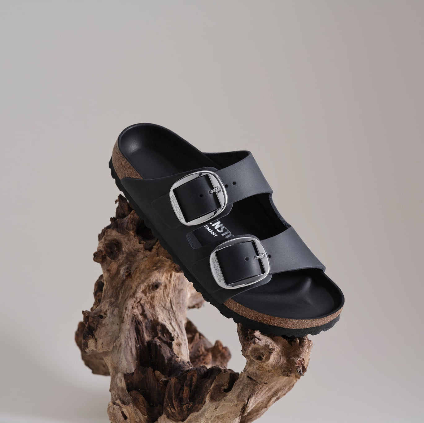 Black sandal with a buckle on a wooden surface