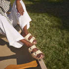 Person wearing white sandals sitting on a step with grass in the background