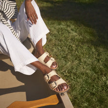 Person wearing white sandals sitting on a step with grass in the background