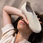 Person wearing a white perforated shoe on a neutral background